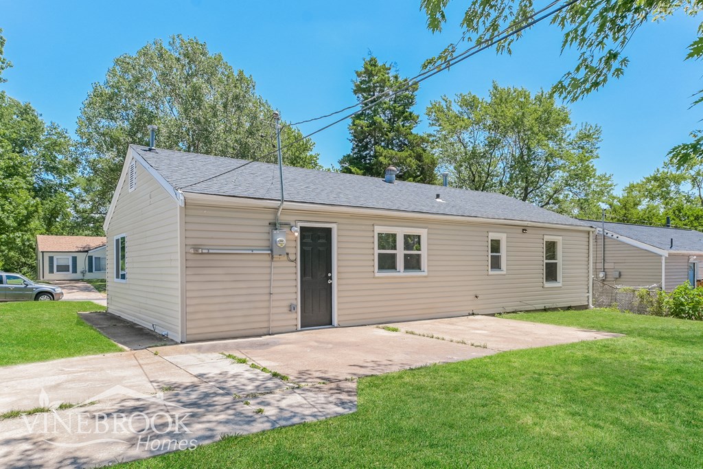 a small tan house with a driveway and a garage door