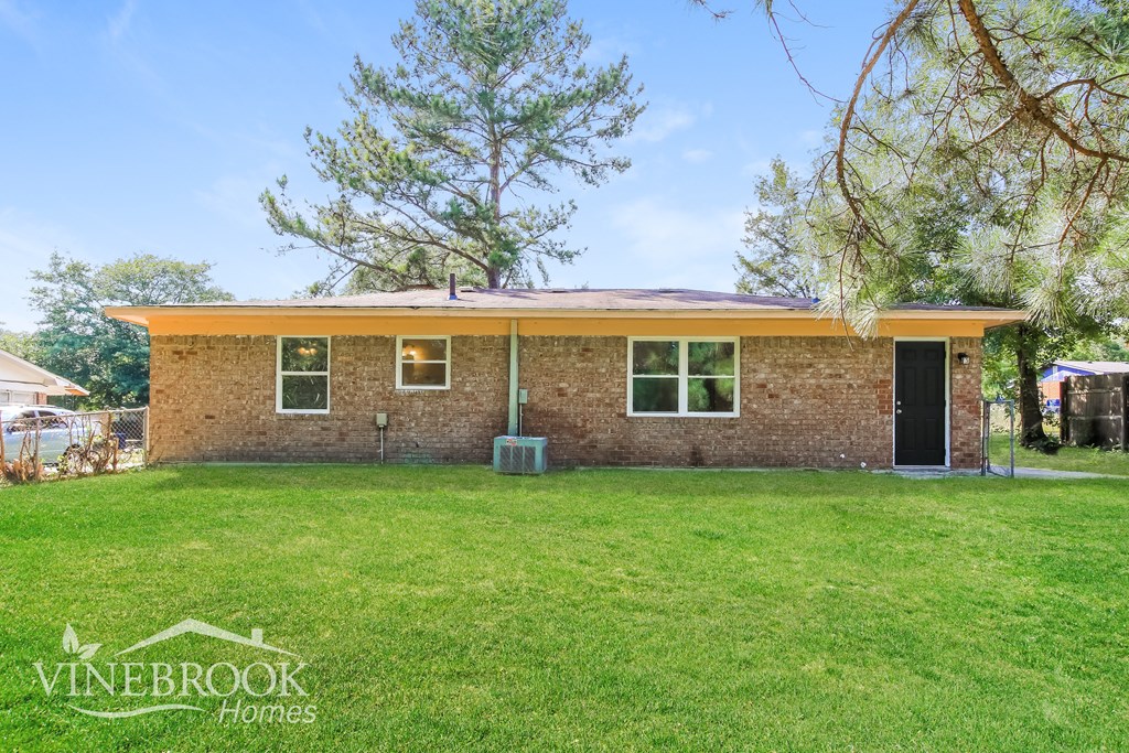 a small brick house with a grassy yard and a tree