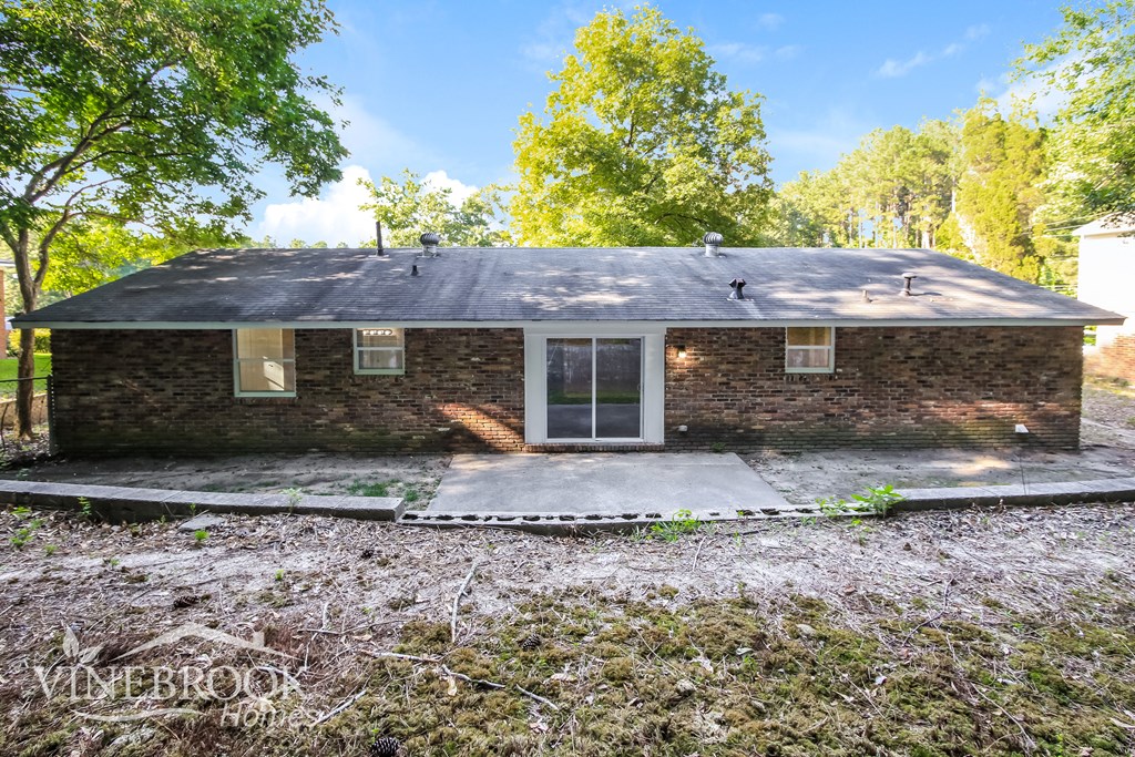 a small brick house with a gray roof and some trees