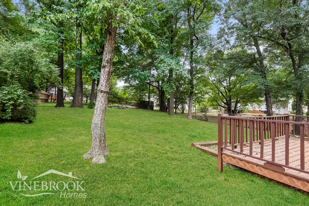 a wooden deck in the middle of a park with trees
