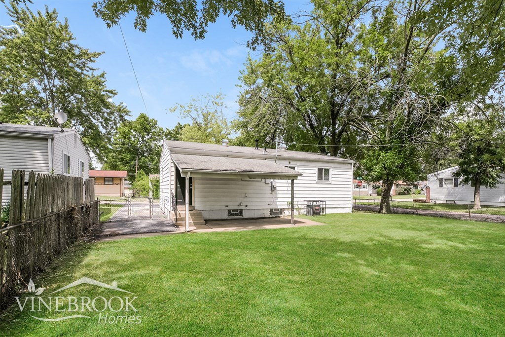 a small white house in a backyard with a lawn and trees
