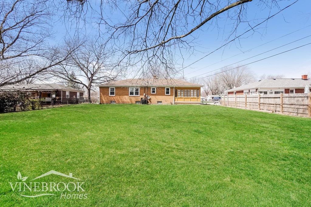 A Vinebrook Homes house with a large lawn and trees in the background.