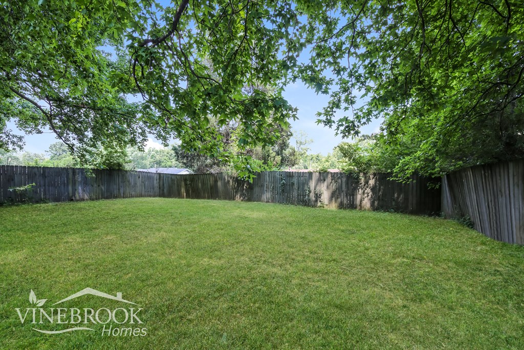 a backyard with a fence and green grass and trees