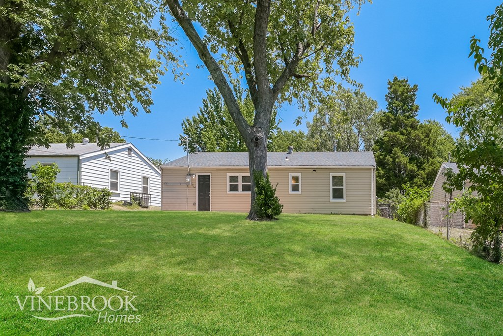 a home with a large yard and a tree in front of it