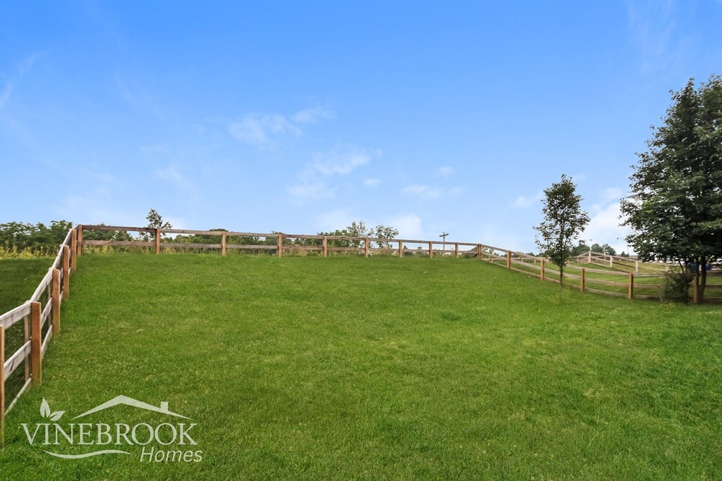 A fenced grassy area with a sign that says Vinebrook Homes.