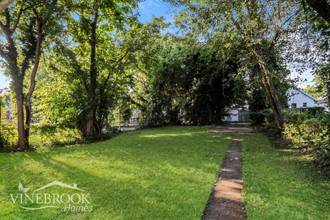 A pathway in a lush green park with trees on both sides.