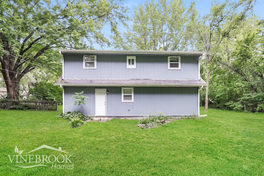 a blue house with a green lawn and trees