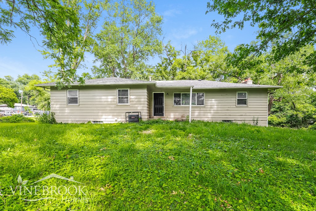a house in the middle of a grassy yard with trees