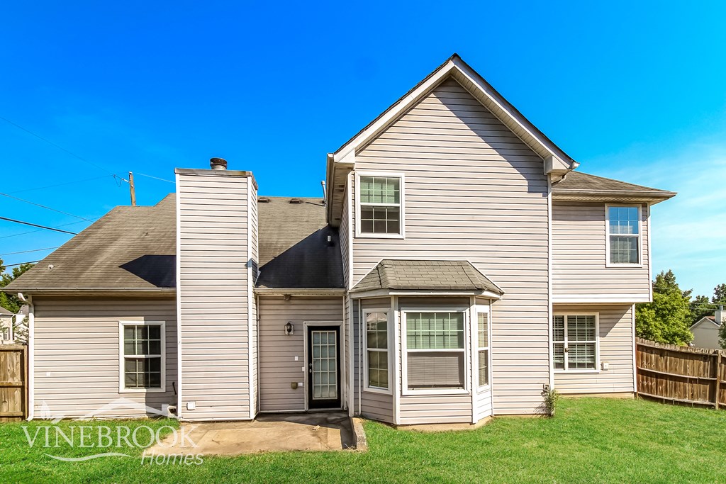 a white house with a brown roof and a green lawn