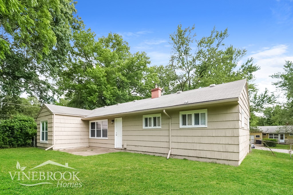 a small tan house with a lawn and some trees