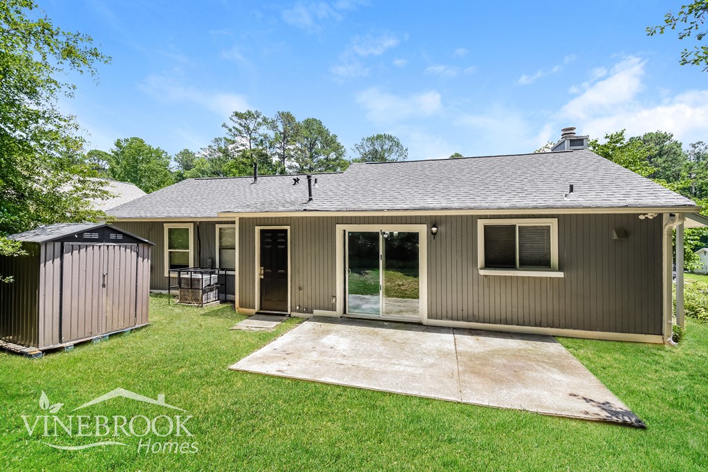 a backyard with a patio and a house with a shed
