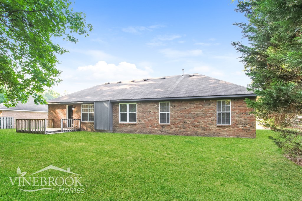 a small brick house with a yard and a deck