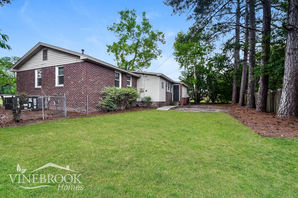 a backyard with a house and a lawn and trees
