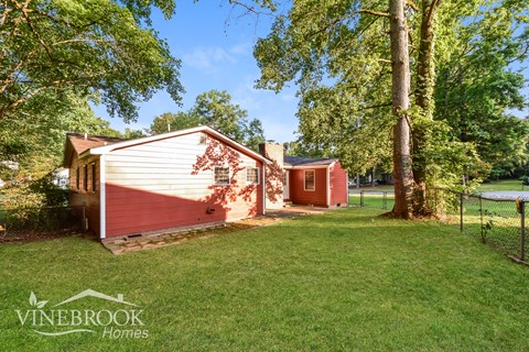 a small red and white house with a yard and trees