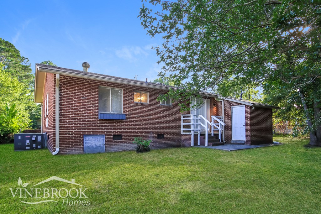 a small brick house with a lawn and a white staircase