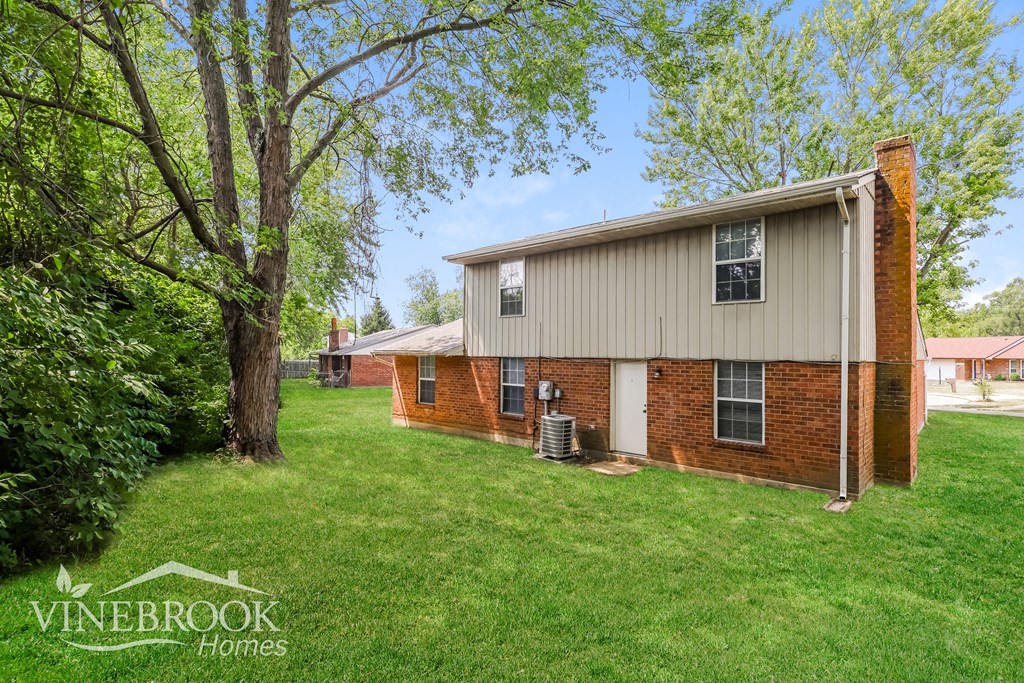 a white and brick house with a yard and a tree
