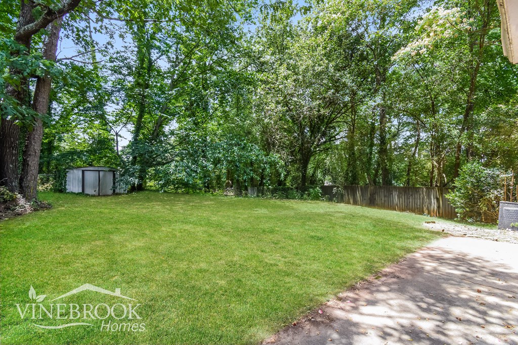 a backyard with green grass and trees and a sidewalk