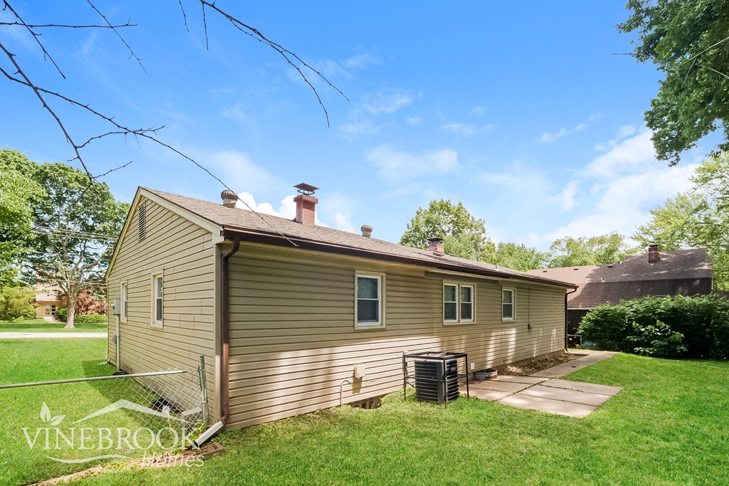 a small brown house with a yard and a gate