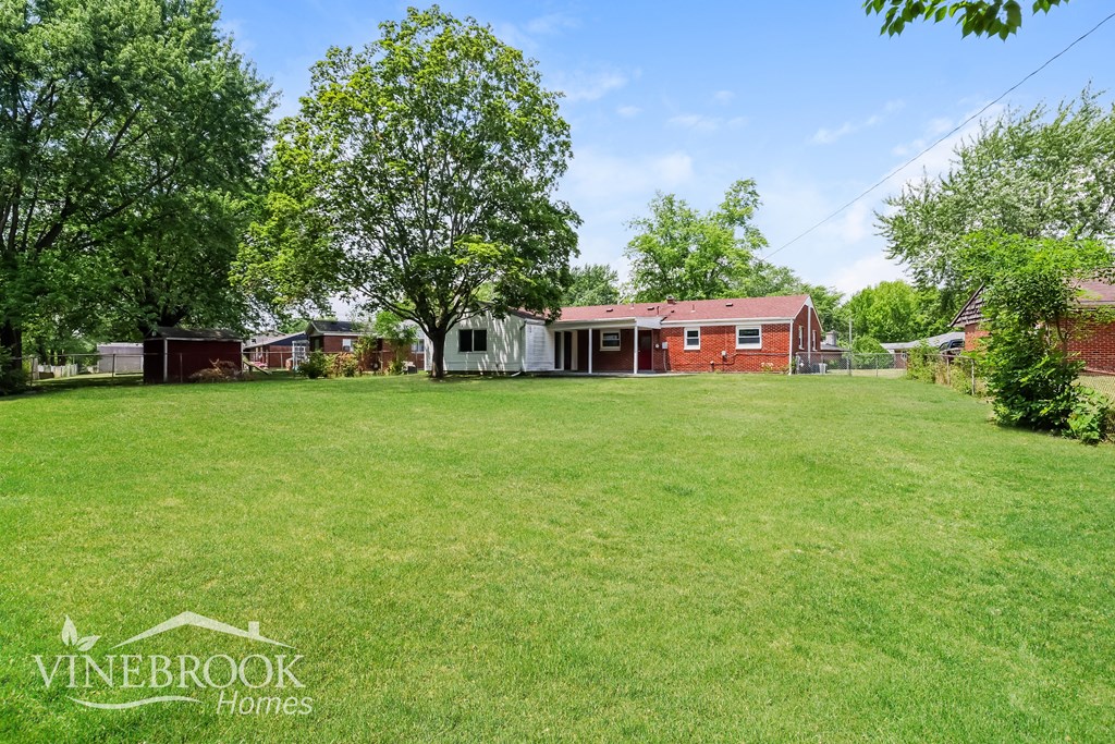 a large lawn in front of a red brick house