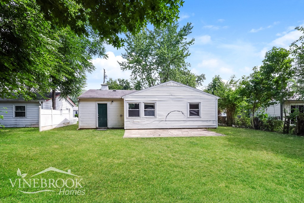 a small white house in the middle of a grassy yard