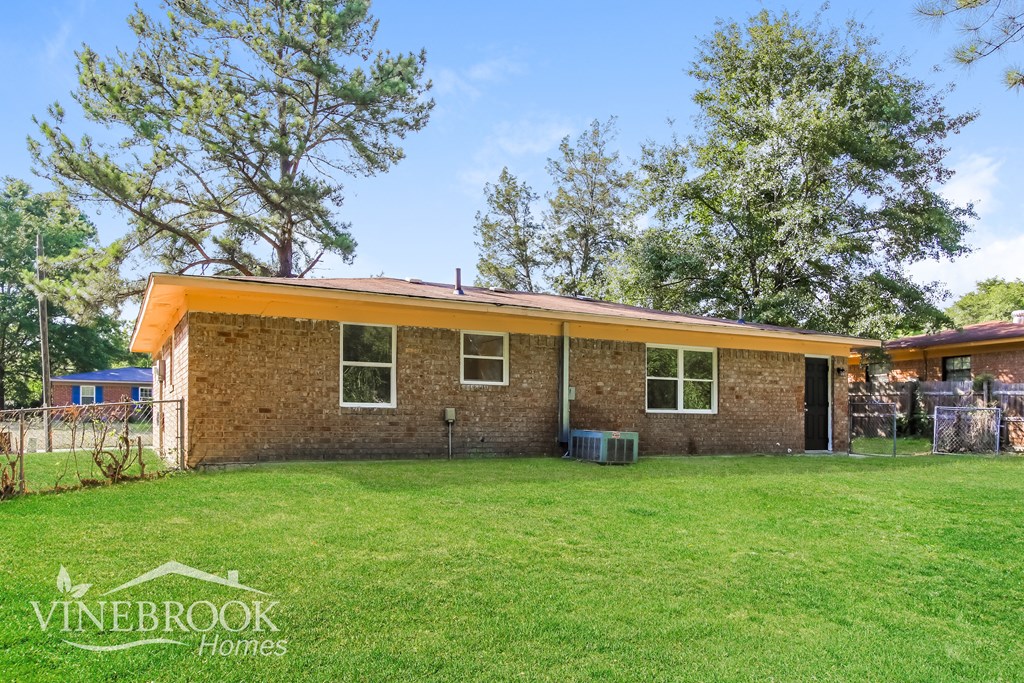 a small brick house with an orange roof on a grass yard