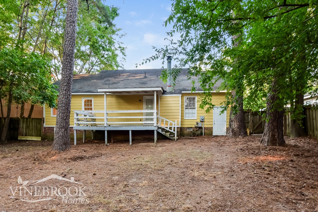 a yellow house with a porch and trees