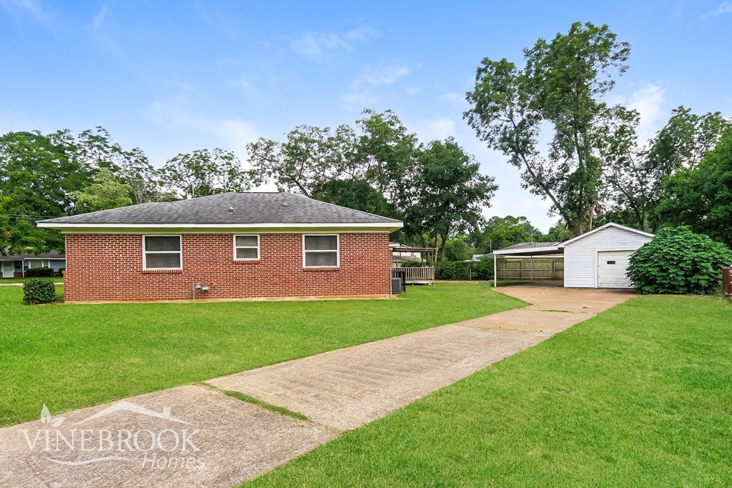a small brick house with a lawn and a driveway