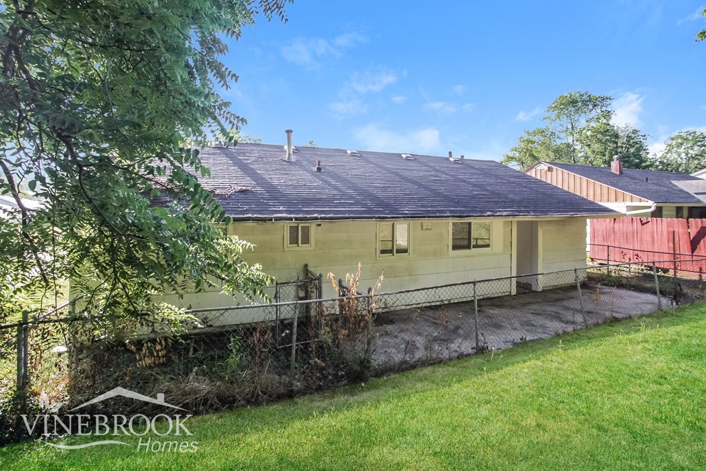 the back of a yellow house with a yard and a fence