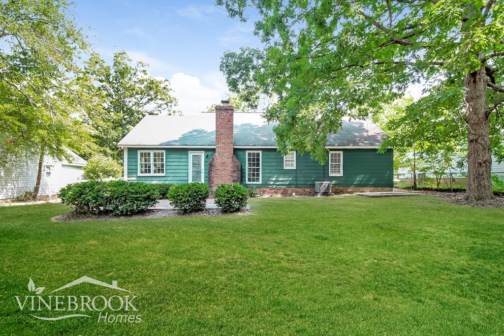 a green house with a lawn and trees