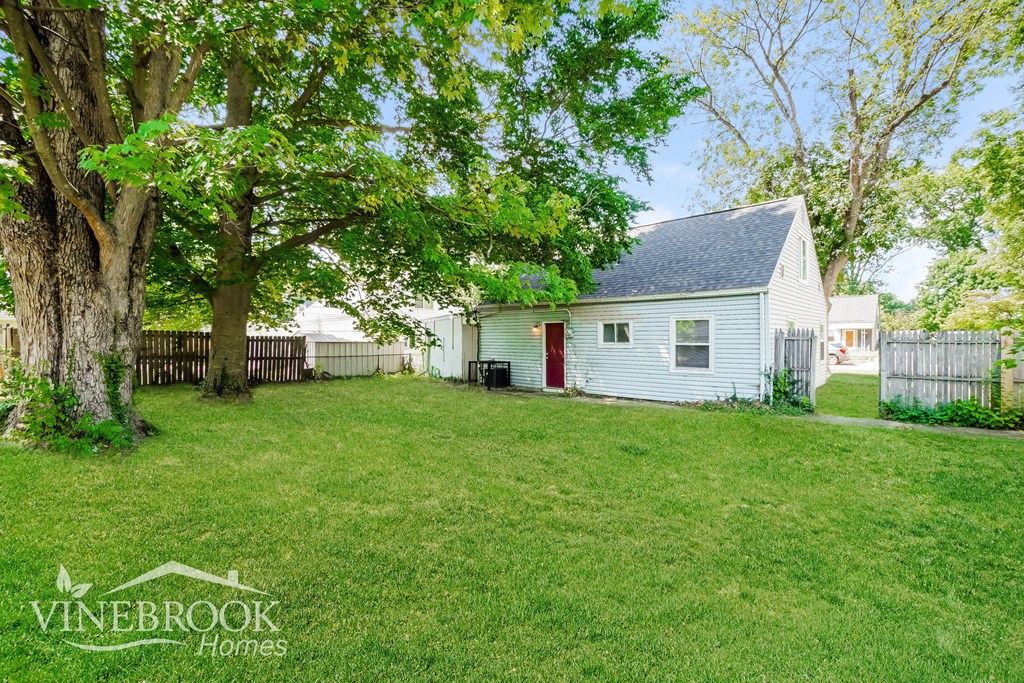 a backyard with a white house and a tree
