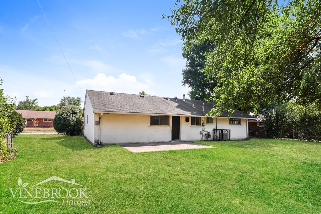 the backyard of a white house with a yard and trees