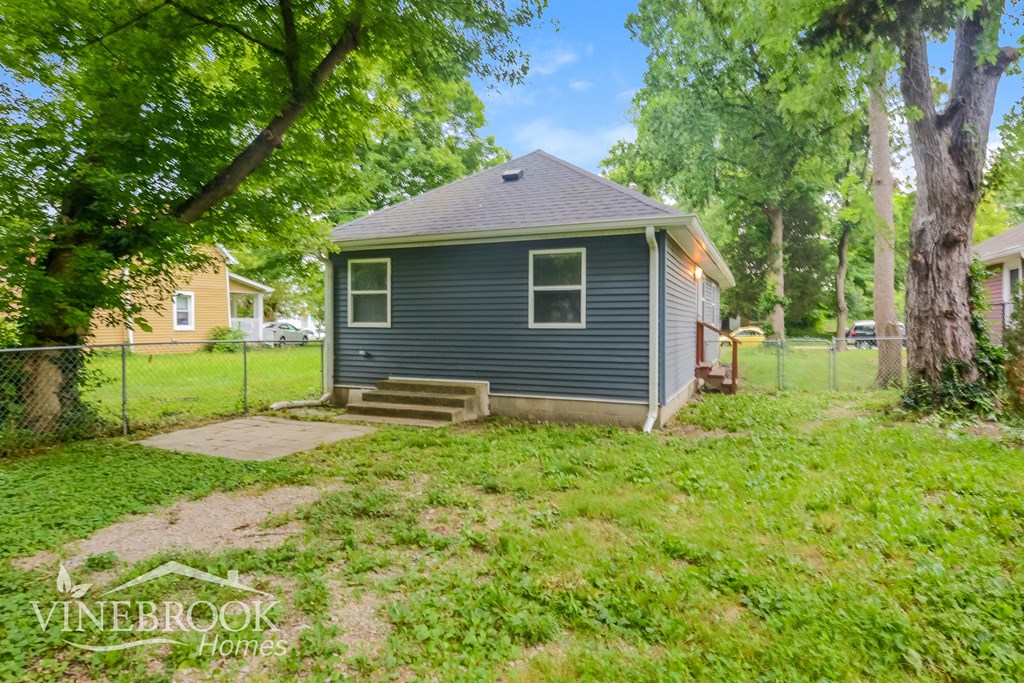 a small blue house with a yard and a chain link fence