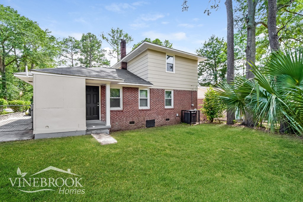 a small brick house with a lawn and trees