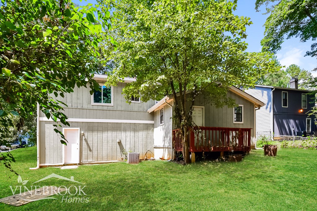 a backyard with a deck and a house and a tree