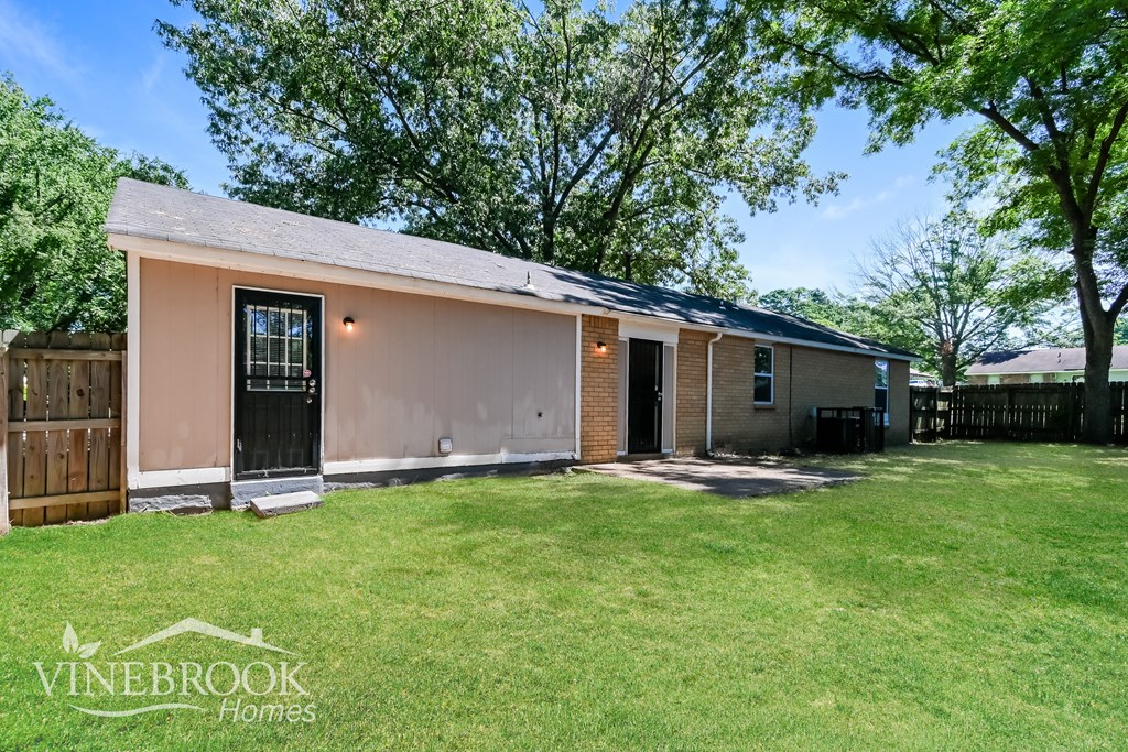 a small brown house with a lawn and trees