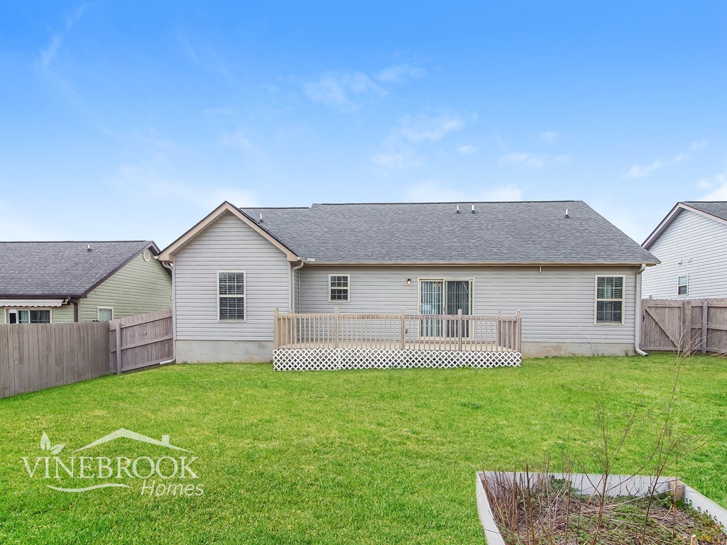 A house with a fence and a Vinebrook Homes logo.