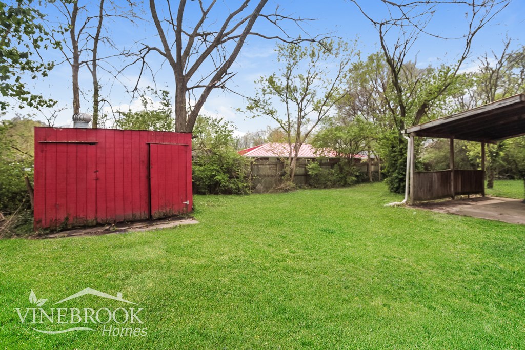 A red shed sits in a grassy backyard.