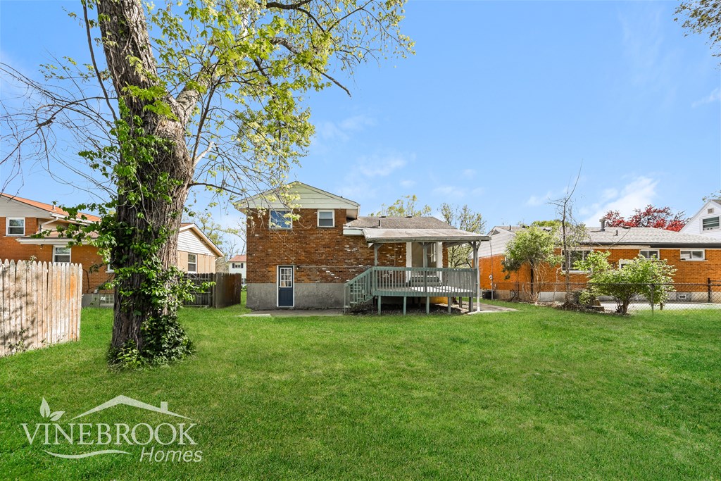 A Vinebrook Homes sign is on a tree in a grassy backyard.