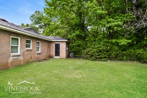 A house with a yard and trees in the background.