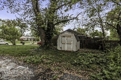 A shed sits in a grassy area surrounded by trees.