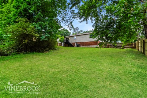 A backyard with a house and trees in the background.