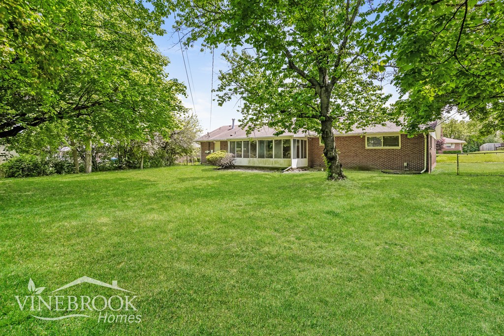A house is surrounded by a green lawn and trees.