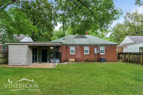 A house with a green lawn and trees in the background is for sale.