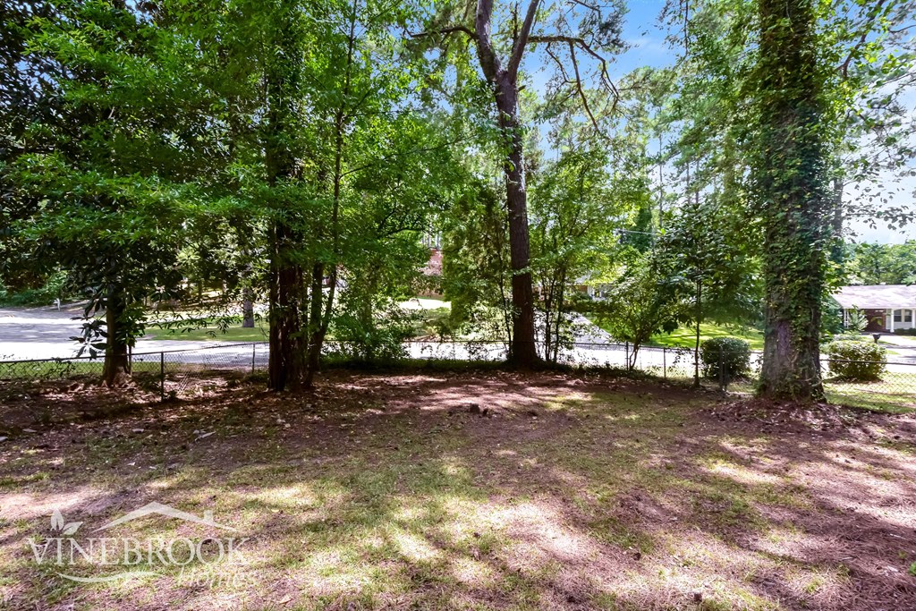 A tree-filled yard with a house in the background.