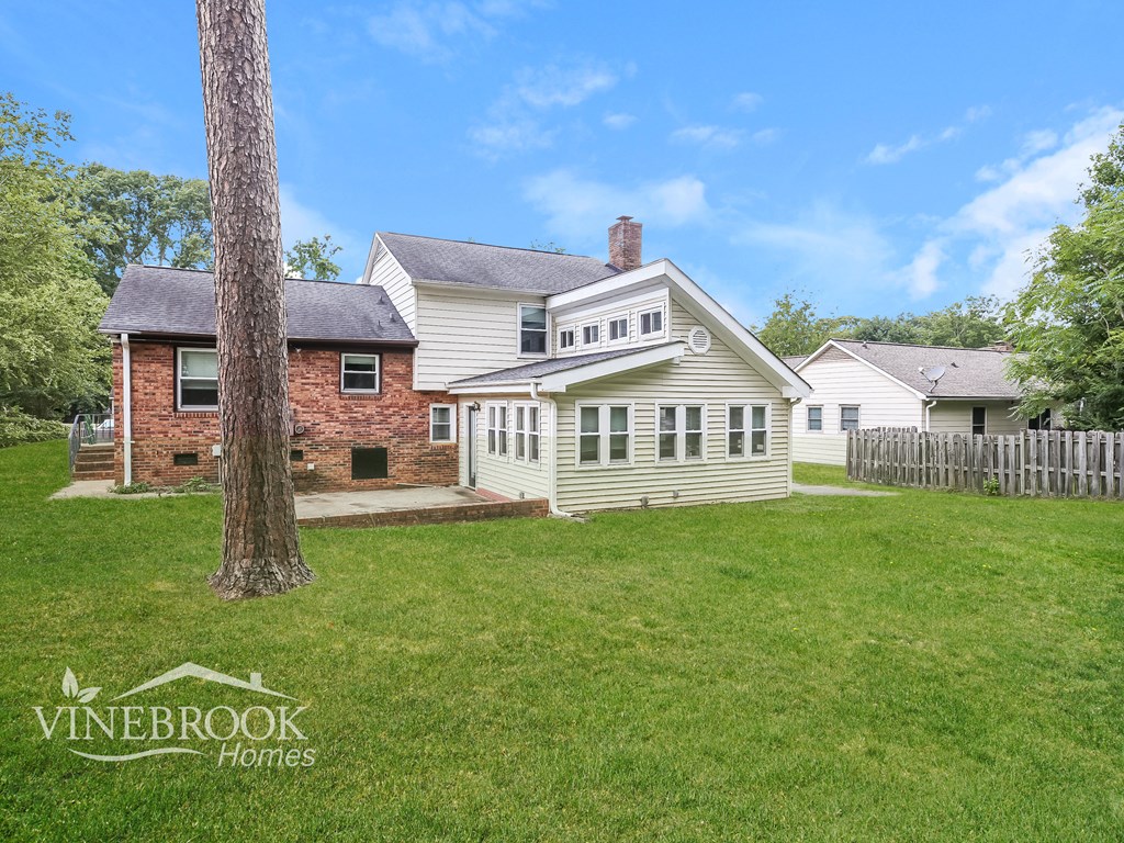 A house with a white fence and a tree in front of it.
