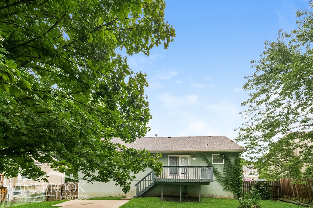 A house with a green lawn and trees in front.