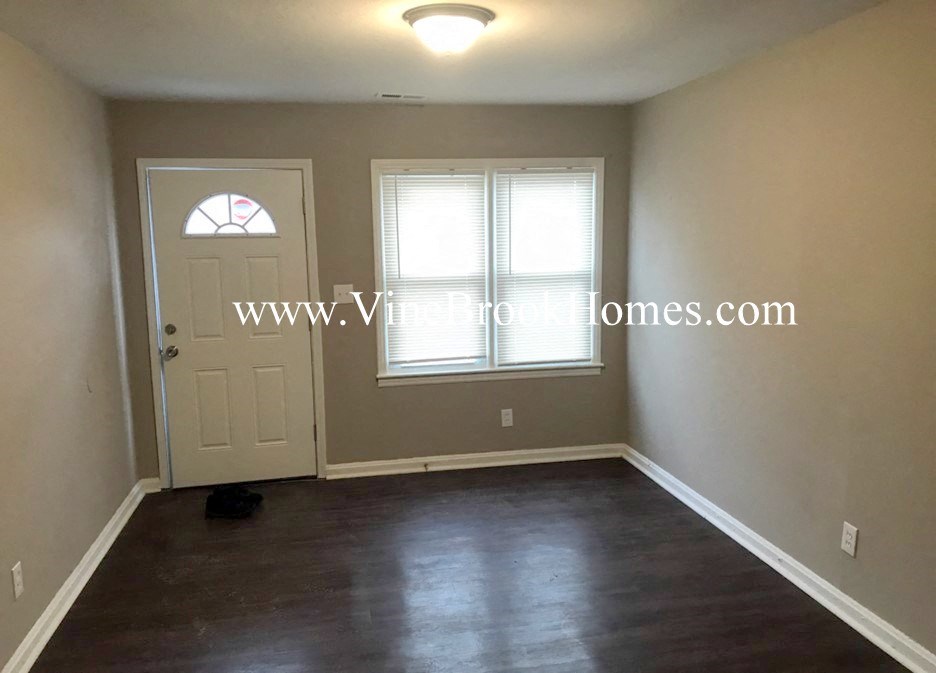 a small empty living room with a white door and window
