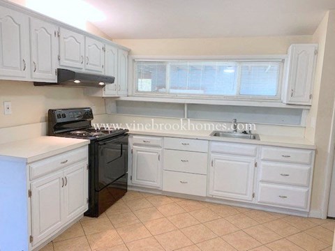 a kitchen with white cabinets and a black stove