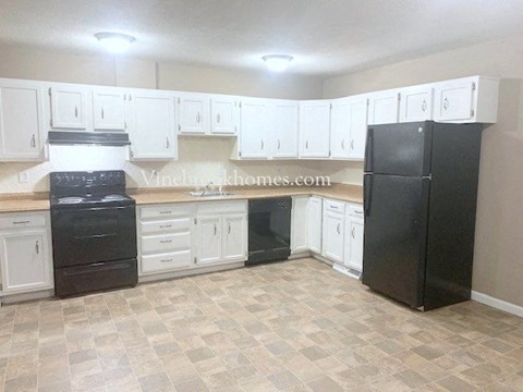 A kitchen with black appliances and white cabinets.