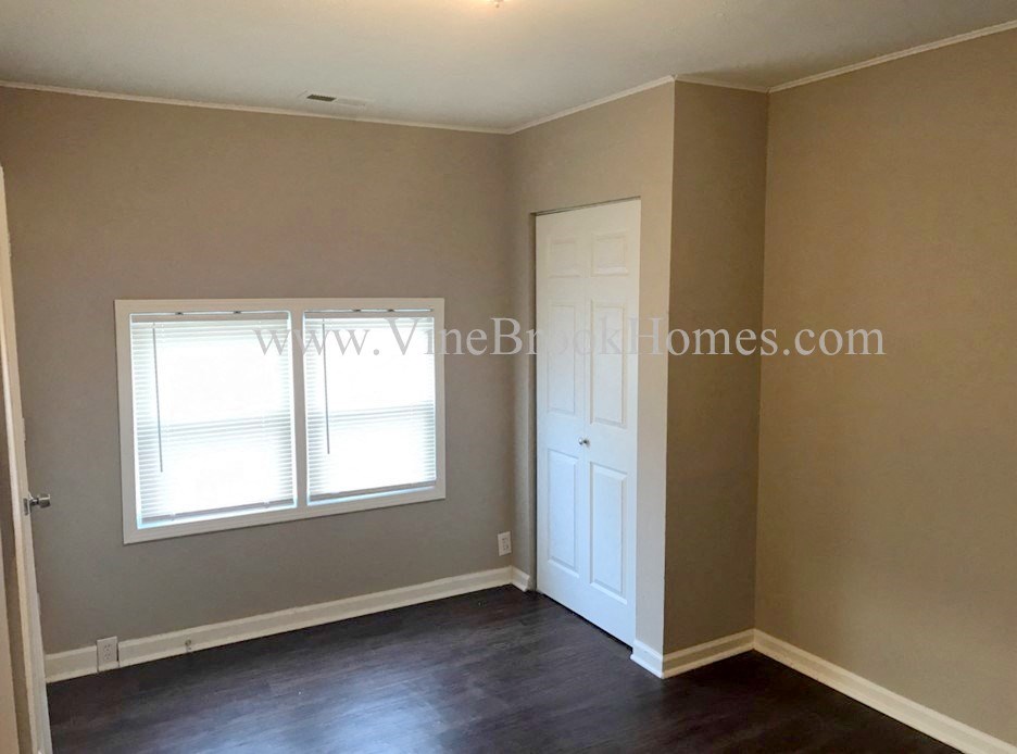 an empty living room with a door and two windows